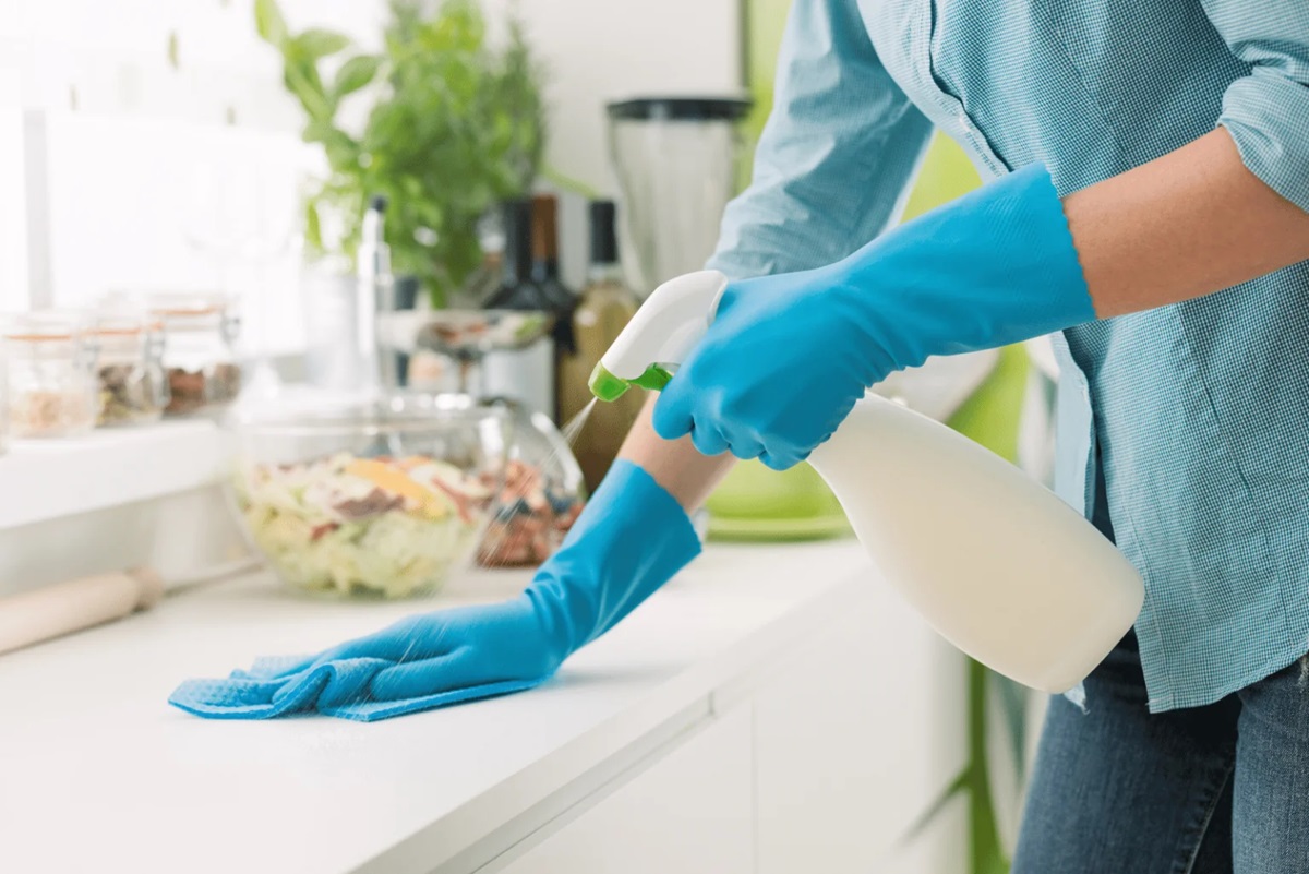 a woman is cleaning kitchen shelves with cleaner and soft cloth