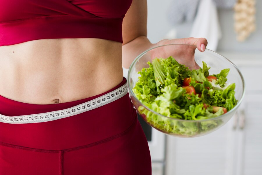 Diet concept with sporty woman in kitchen