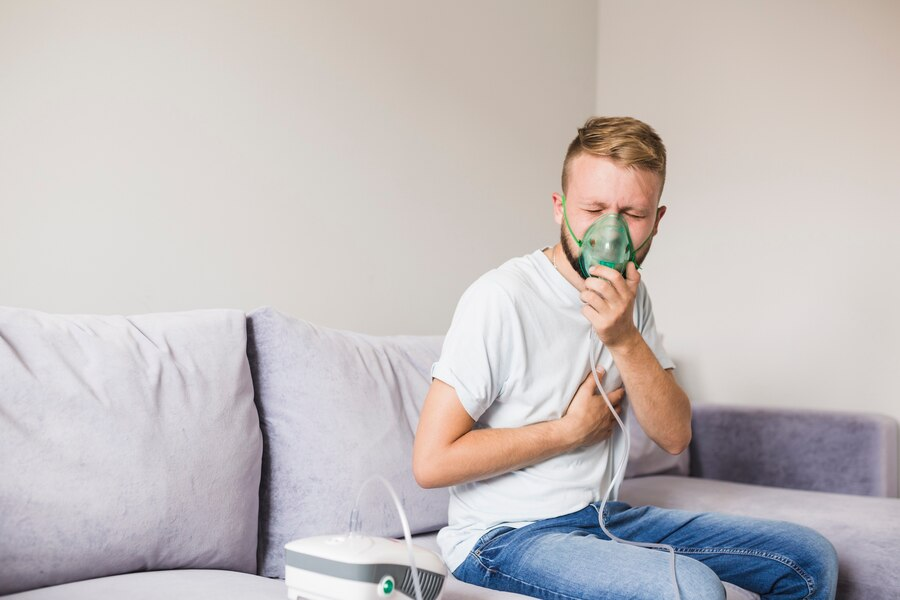 Man using asthma nebulizer holding hand on chest