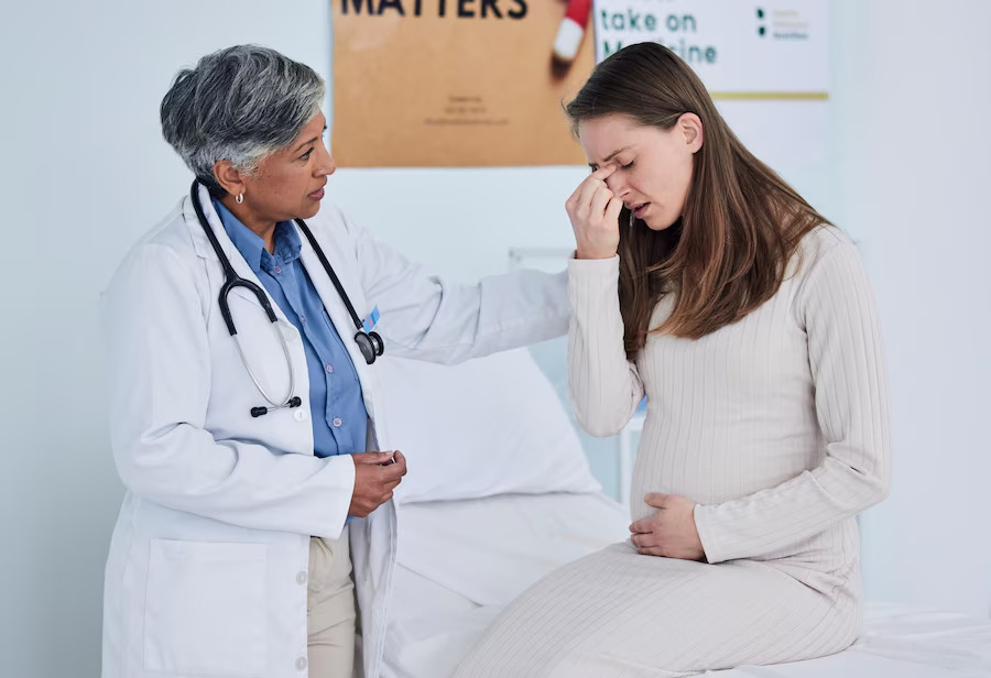 Senior doctor pregnant woman and headache in consultation checkup or appointment at hospital Mature female person medical or healthcare expert checking patient in maternity or pregnancy at clinic.